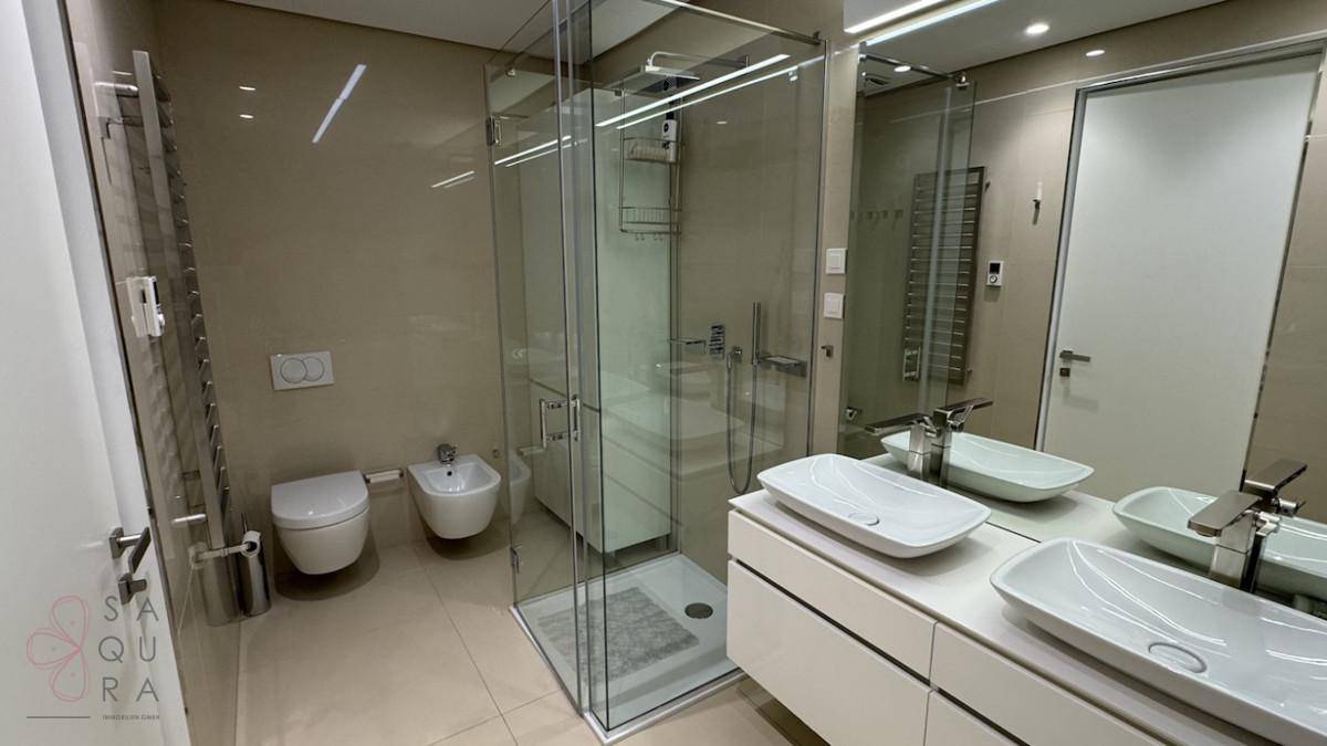 Geräumiges Badezimmer mit Doppelwaschbecken, Bidet, moderner Dusche und großen Spiegeln.