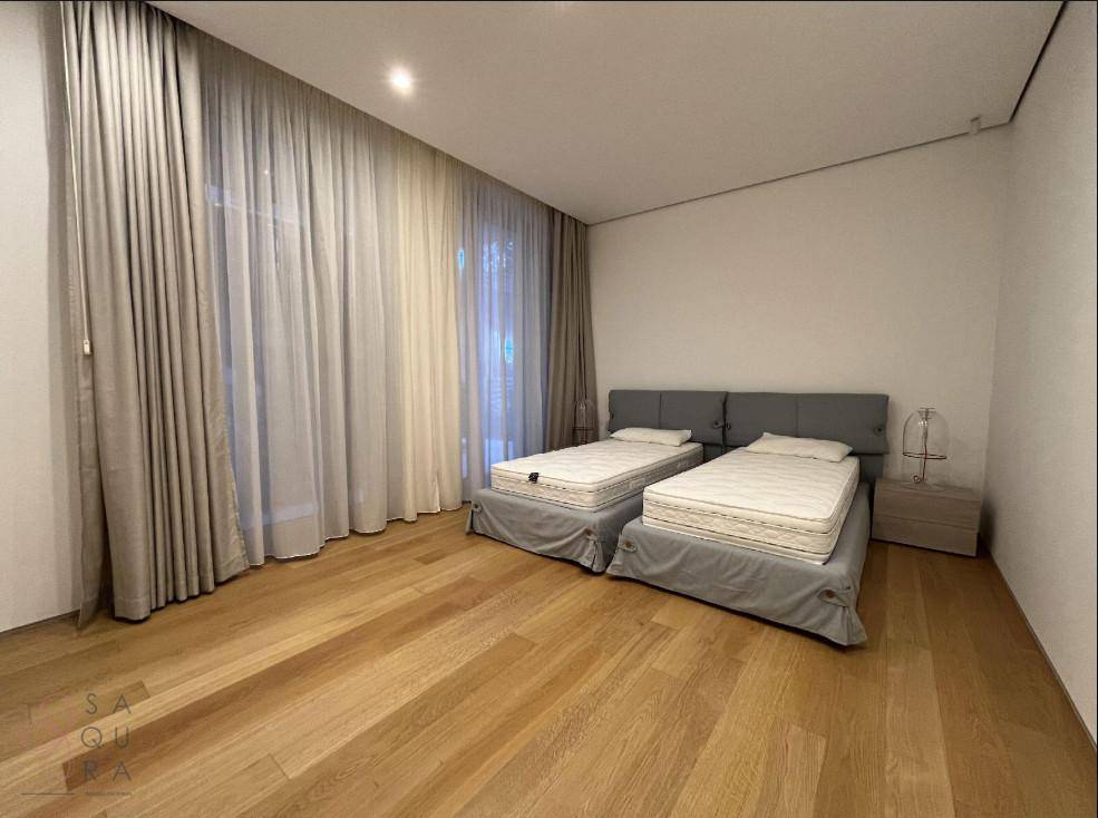 Helles Schlafzimmer mit zwei Einzelbetten, eleganten Vorhängen und hochwertigem Holzboden.