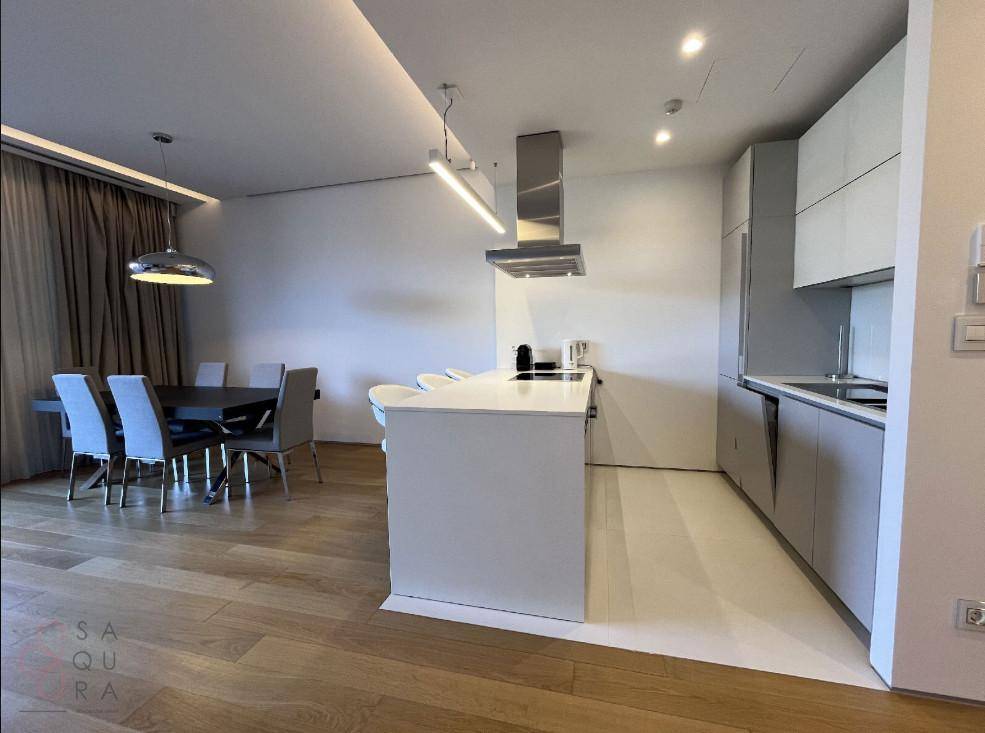 Offener Wohn- und Essbereich mit moderner Küche, Kücheninsel und elegantem Esstisch auf Holzfußboden.