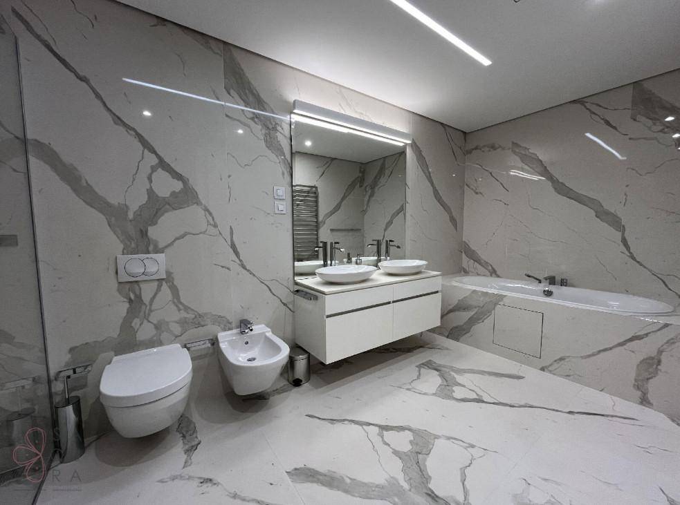 Exklusives Badezimmer mit Marmorfliesen, Doppelwaschbecken, Bidet und Badewanne, für höchsten Komfort.
