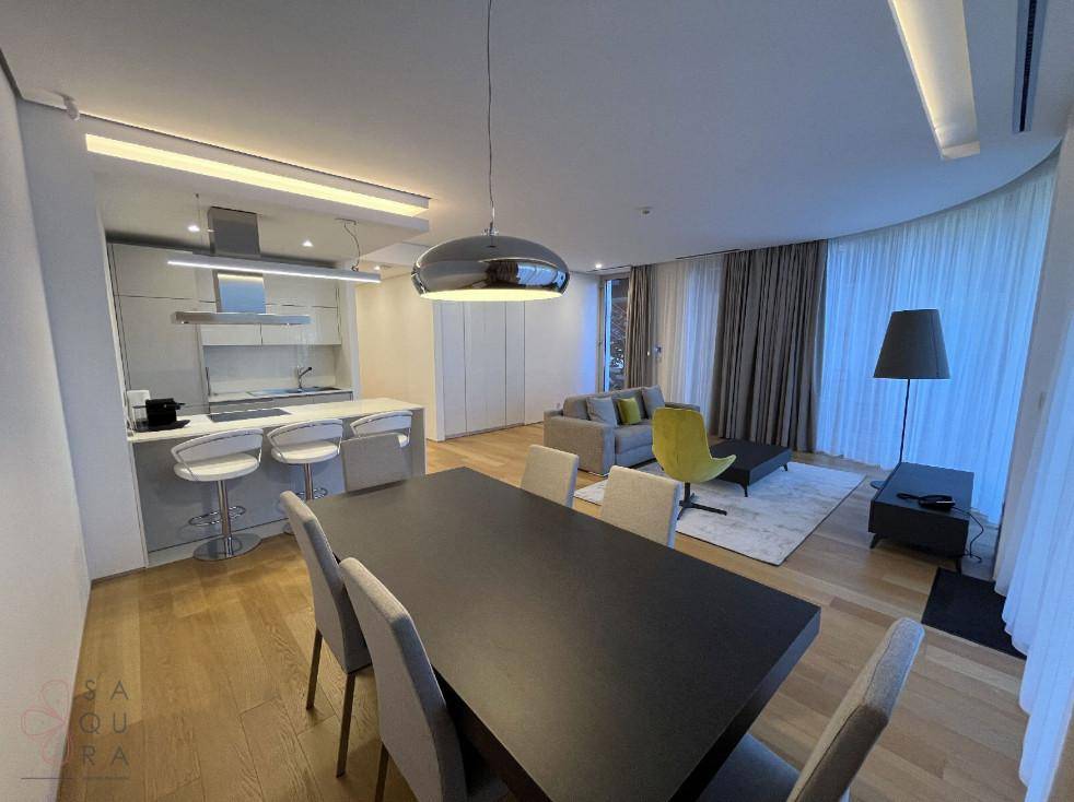 Heller offener Wohn- und Essbereich mit moderner Küche, Holzfußboden und Zugang zu einem Balkon.