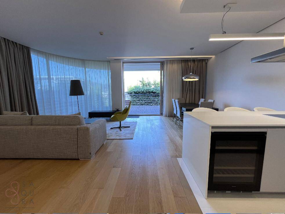 Moderner offener Wohnbereich mit integrierter Küche, Kücheninsel mit Weinkühler und Zugang zum Balkon.