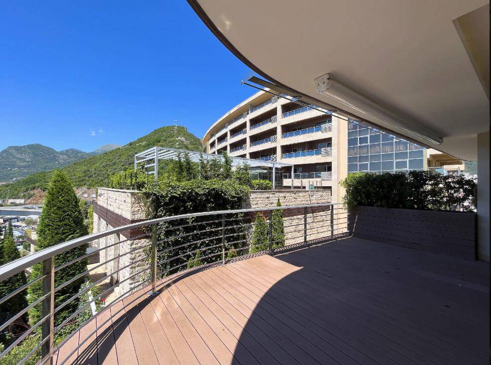Geschwungene Terrasse mit Holzboden und Panoramablick auf moderne Architektur und die umliegenden Hügel.