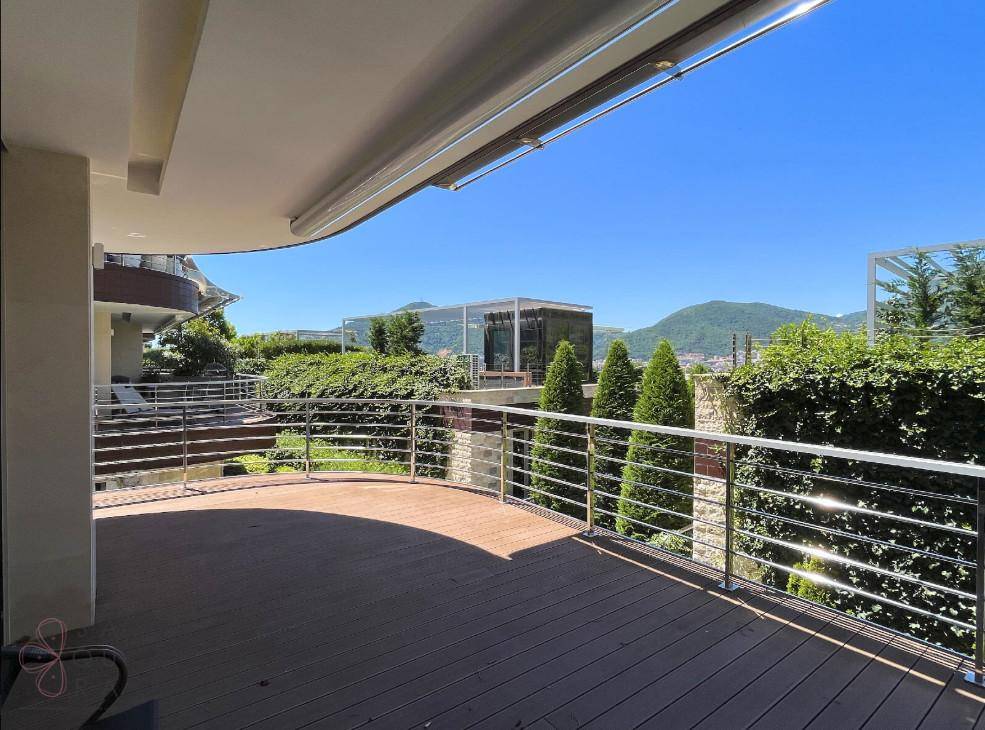 Geräumige Terrasse mit Holzboden und Metallgeländer, bietet einen weiten Blick auf die grüne Umgebung.