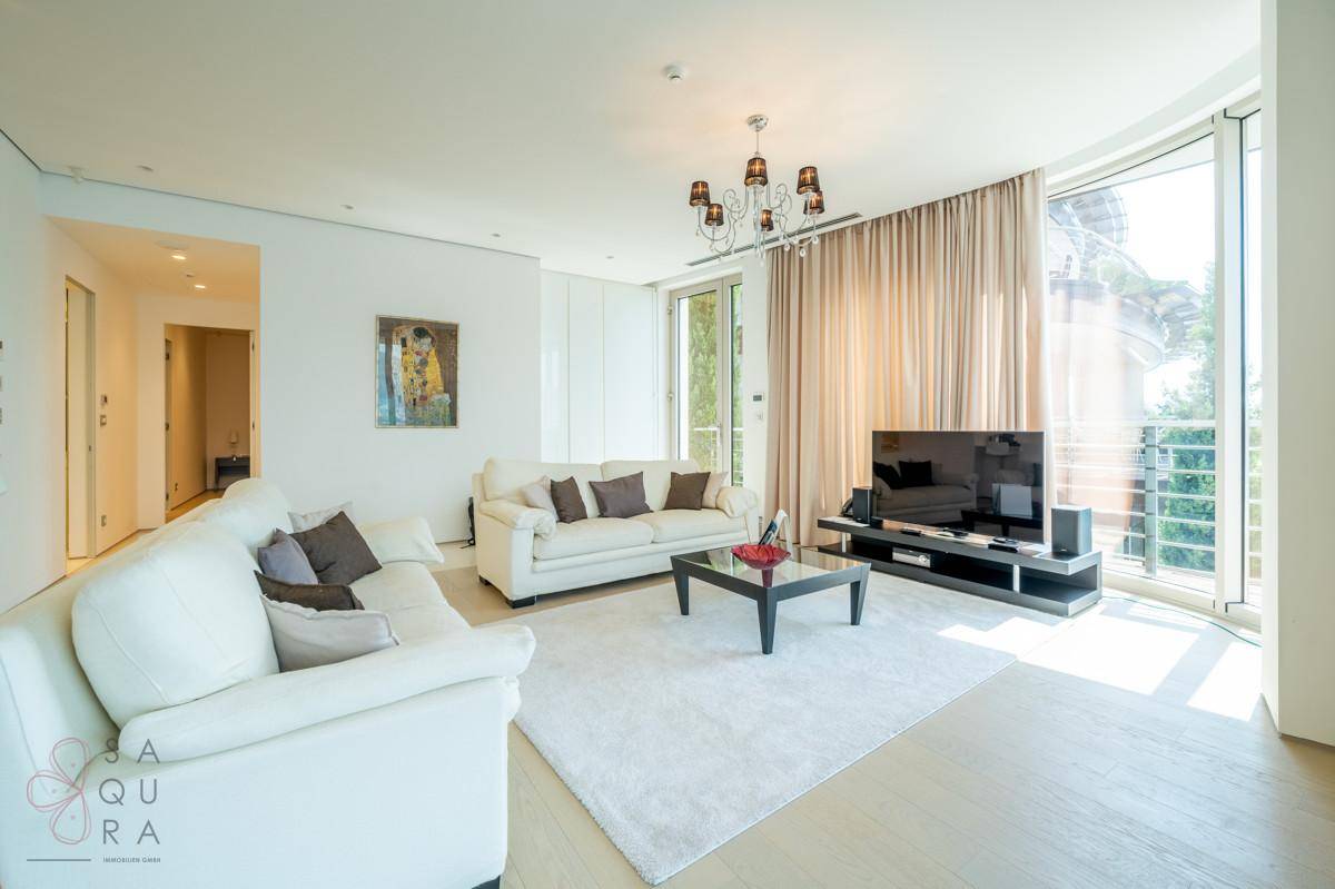 Ein elegantes Wohnzimmer mit bequemen Sofas, einem Couchtisch und großen Fenstern mit Blick ins Grüne.