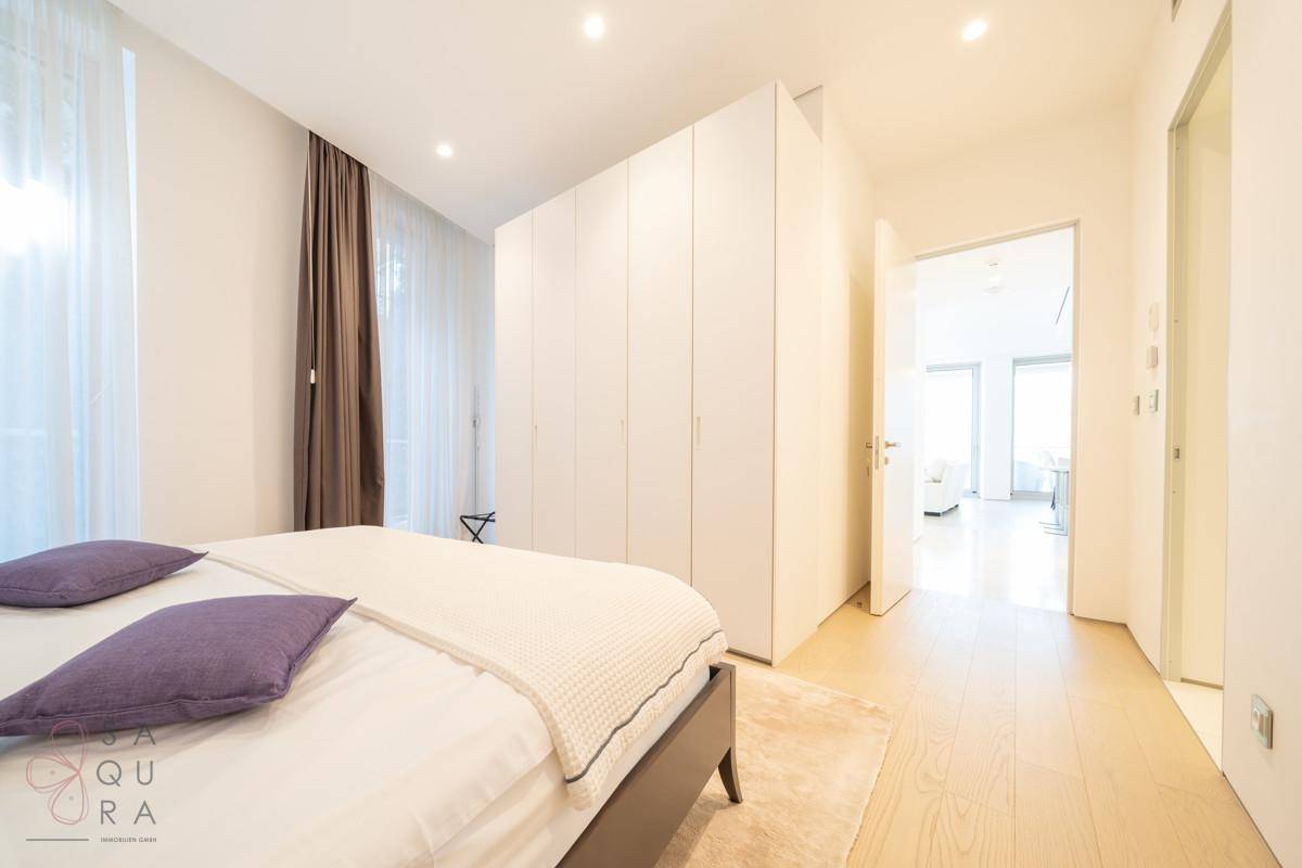 Helles Schlafzimmer mit Doppelbett, Einbauschränken und Holzboden.