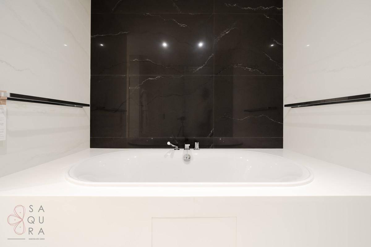 Elegante Badewanne in einem modernen Badezimmer mit schwarzen Marmorfliesen.