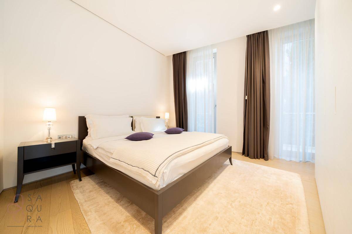 Geräumiges Schlafzimmer mit Doppelbett, Teppich und großen Fenstern.