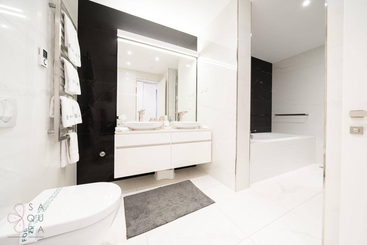 Modernes Badezimmer mit Doppelwaschbecken, Badewanne und beheiztem Handtuchhalter.