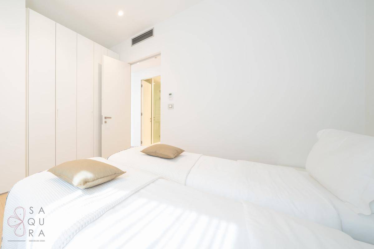 Modernes Schlafzimmer mit Einbauschränken, Holzboden und Zugang zum Badezimmer.