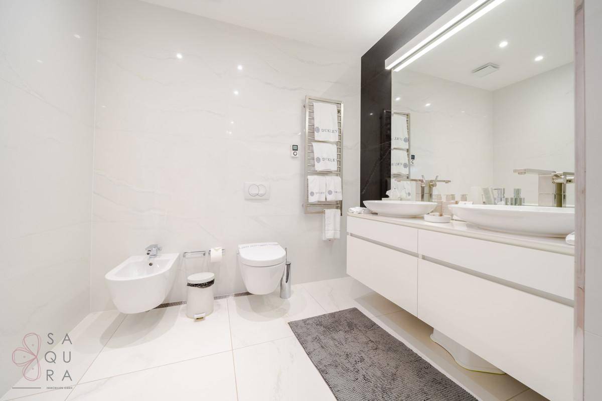 Elegantes Badezimmer mit Bidet, Toilette und Doppelwaschbecken.
