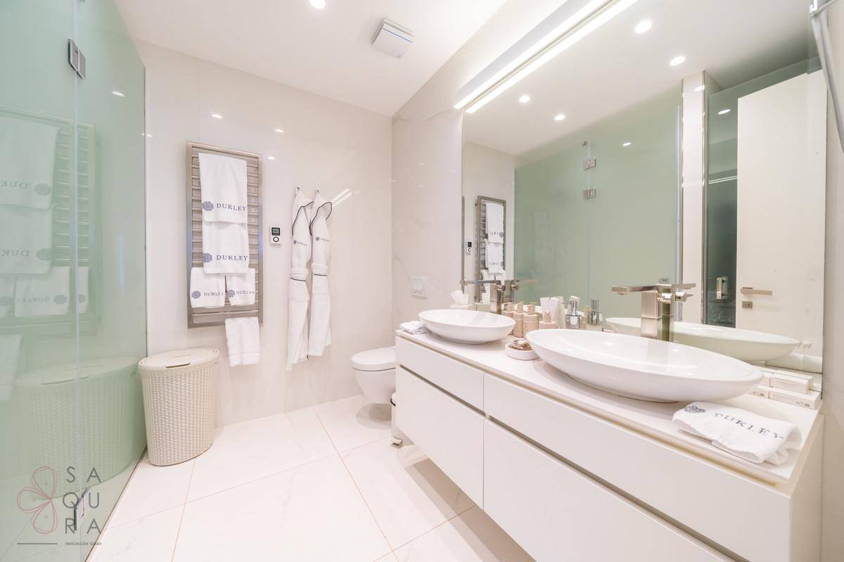 Luxuriöses Badezimmer mit Doppelwaschbecken, großer Spiegelfläche und begehbarer Dusche.