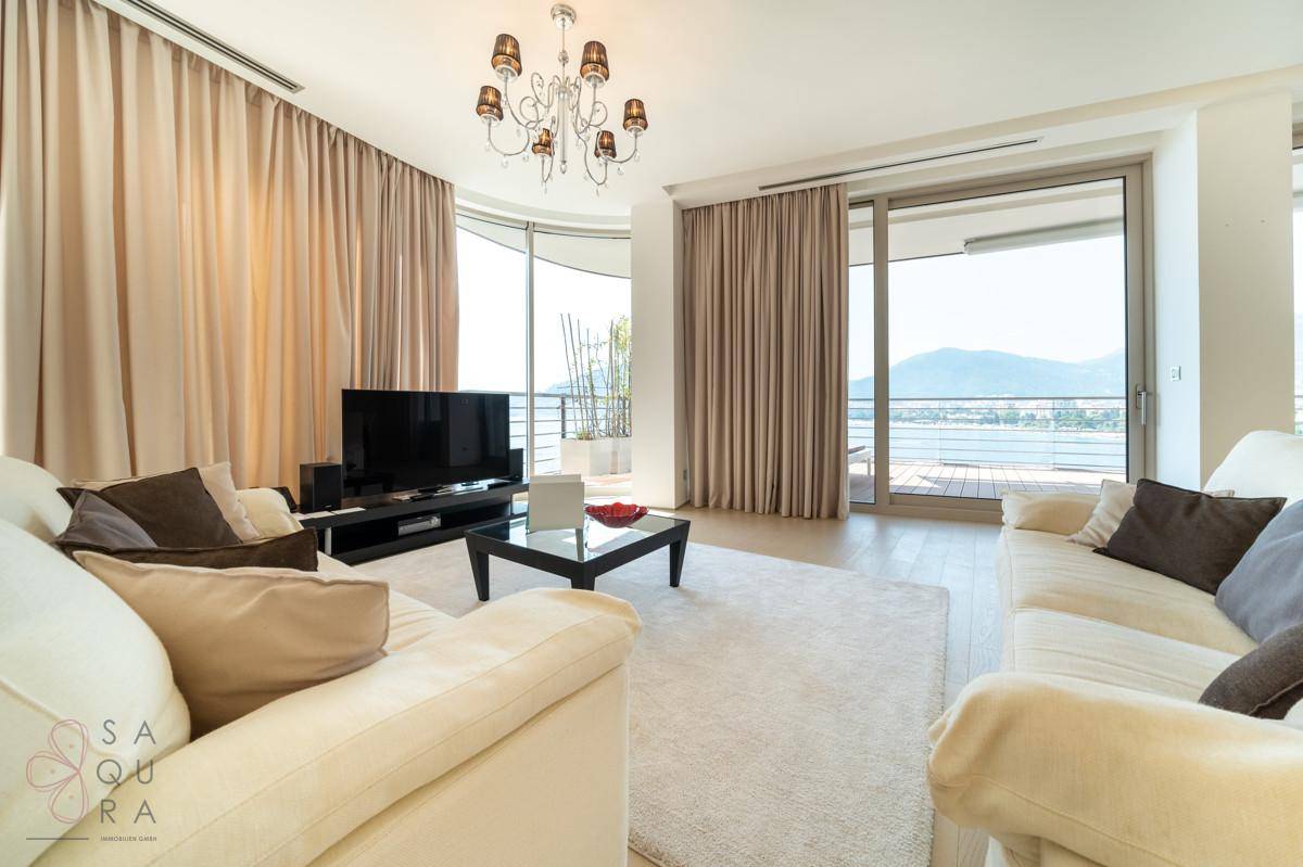 Ein stilvolles Wohnzimmer mit zwei Sofas, einem Couchtisch und großen Fenstern, die viel Tageslicht hereinlassen.