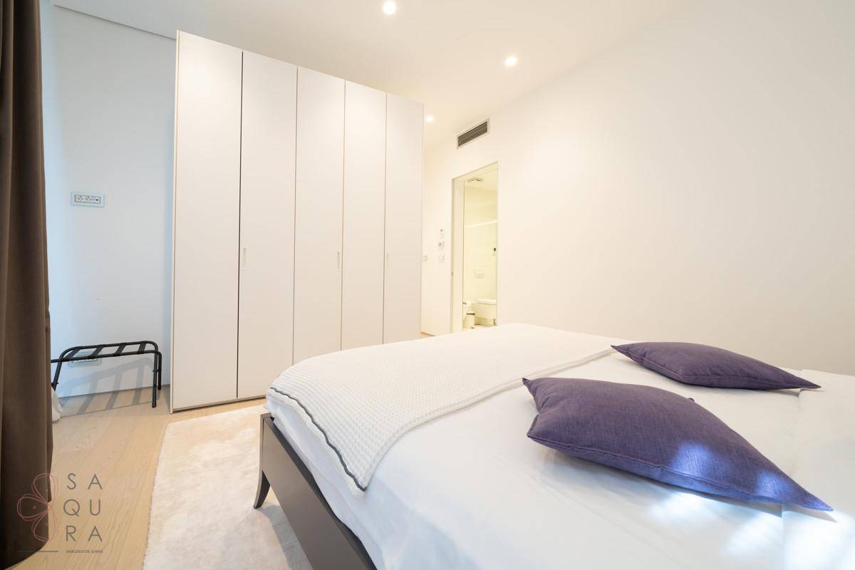 Modernes Schlafzimmer mit Doppelbett, Einbauschränken und Zugang zum Badezimmer.