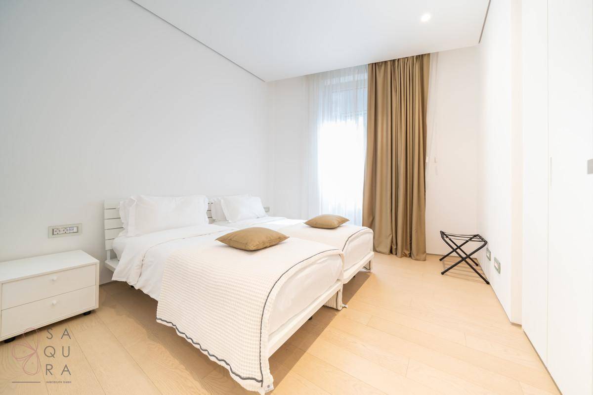 Helles Schlafzimmer mit zwei Einzelbetten, Holzboden und Vorhängen.