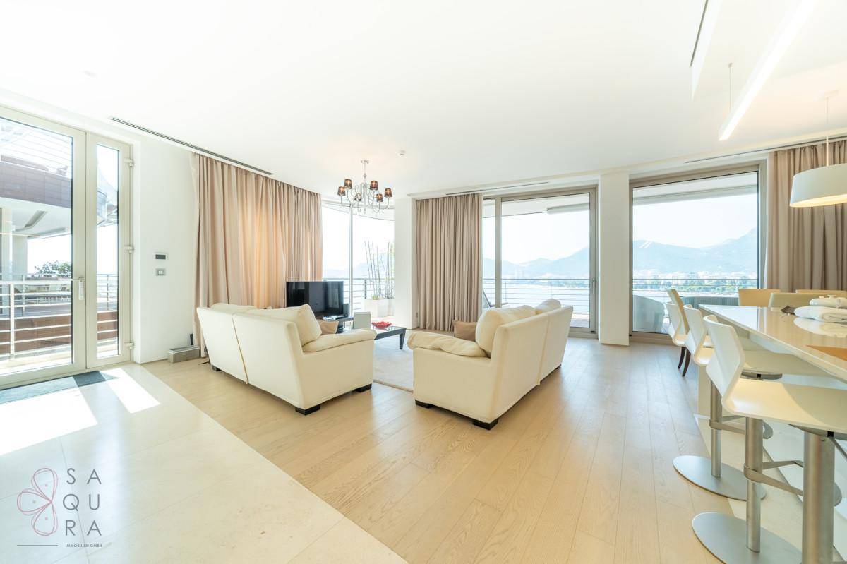 Geräumiger Wohn- und Essbereich mit offener Küche, hellen Möbeln und Zugang zu einem Balkon mit Aussicht.