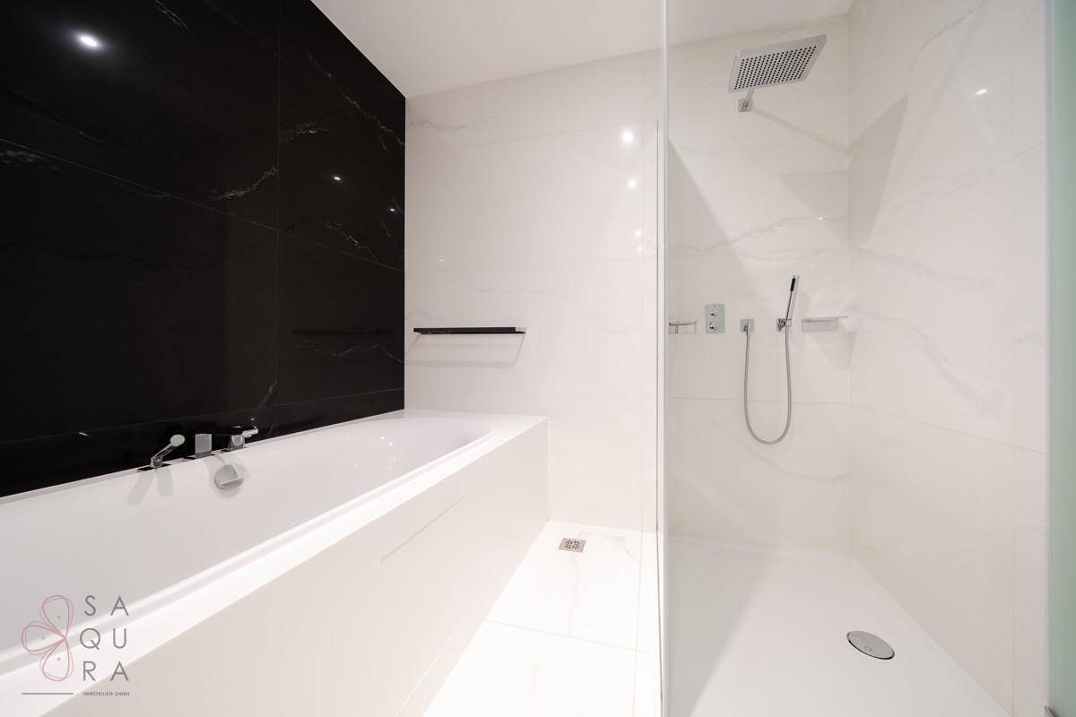 Modernes Badezimmer mit Badewanne, Regendusche und eleganten schwarzen Akzenten.