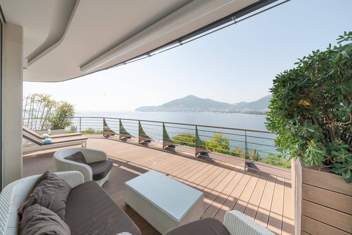Sonnenterrasse mit Loungemöbeln, Pflanzen und weitem Blick auf das Meer.
