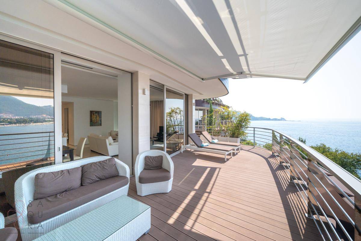 Geräumige Terrasse mit Loungemöbeln, Markise und Panoramablick auf die Küste.