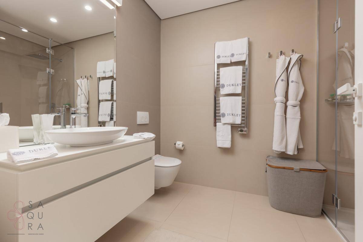Ein modernes Badezimmer mit schwebendem Waschtisch, Wand-WC und einer geräumigen begehbaren Dusche.