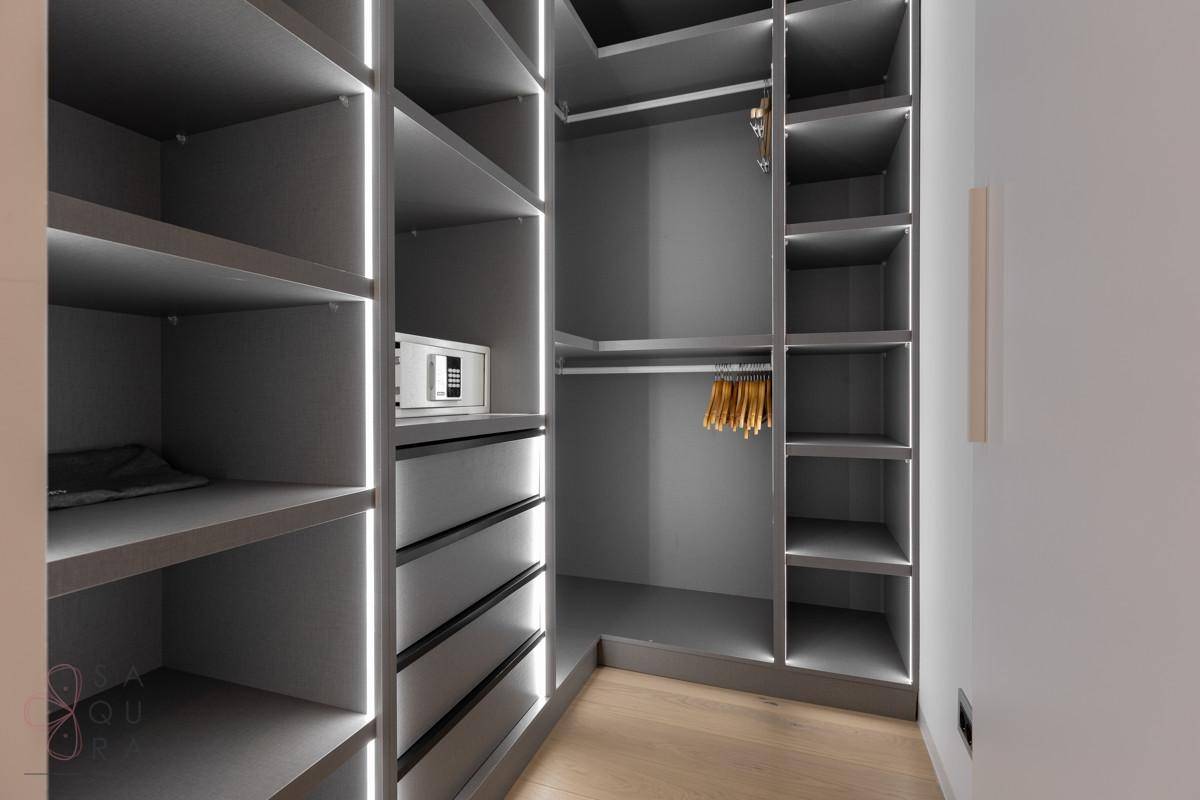 Begehbarer Kleiderschrank mit modernen grauen Regalen und integrierter Beleuchtung.