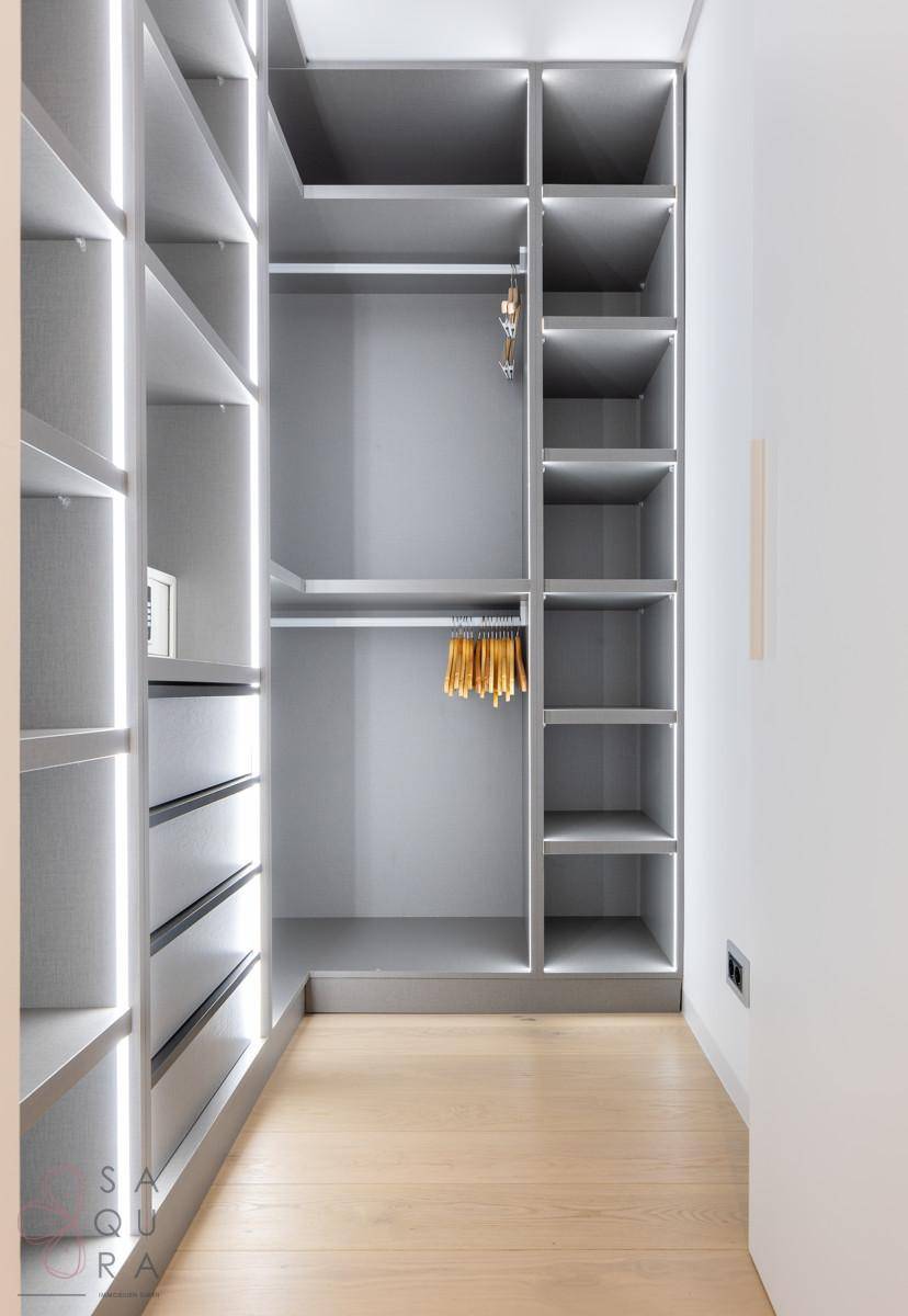 Geräumiger begehbarer Kleiderschrank mit viel Stauraum und indirekter Beleuchtung.