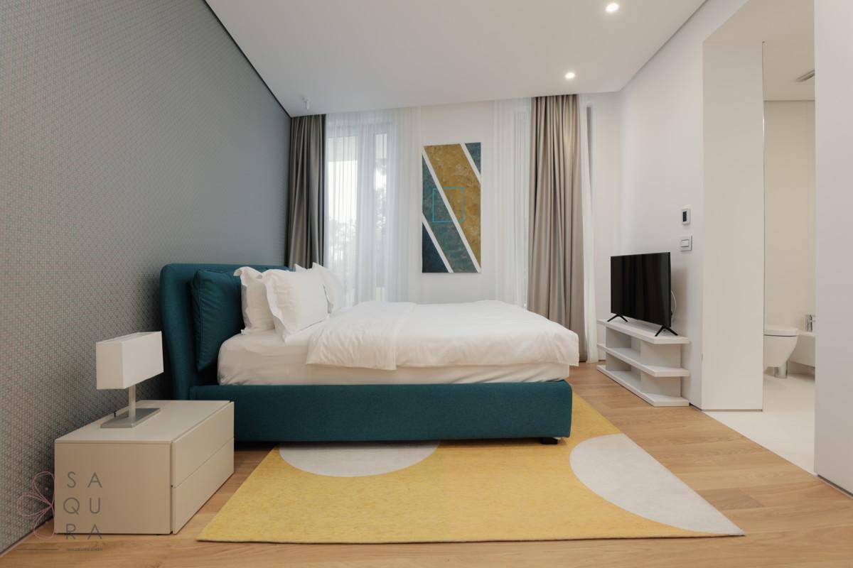 Modernes Schlafzimmer mit großem Bett, Holzboden und einem Fernseher, mit Zugang zu einem Badezimmer.