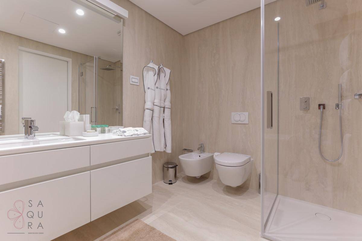 Elegantes Badezimmer mit Doppelwaschbecken, Bidet, Toilette und einer geräumigen begehbaren Dusche.