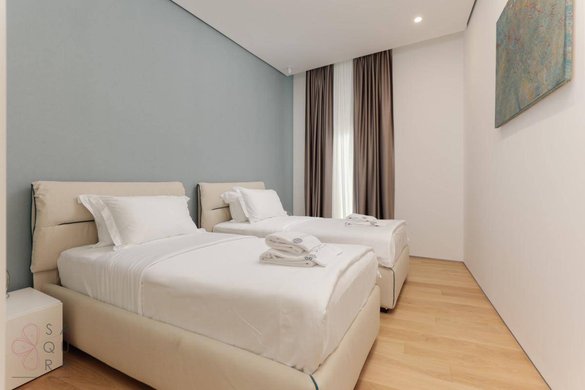Modern eingerichtetes Schlafzimmer mit zwei Einzelbetten, Holzboden und einem Kunstwerk an der Wand.