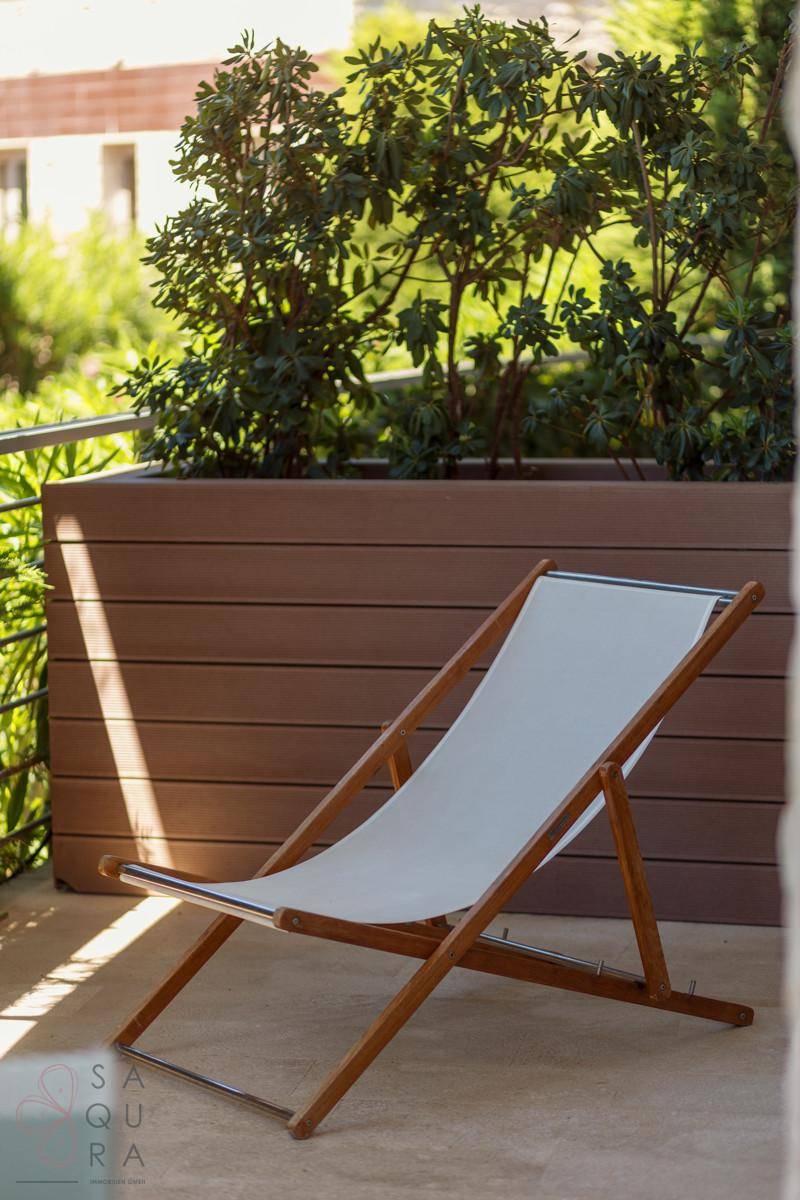Gemütlicher Balkon mit Liegestuhl und Pflanzenkübeln, ideal zum Entspannen im Freien und Sonnenbaden.