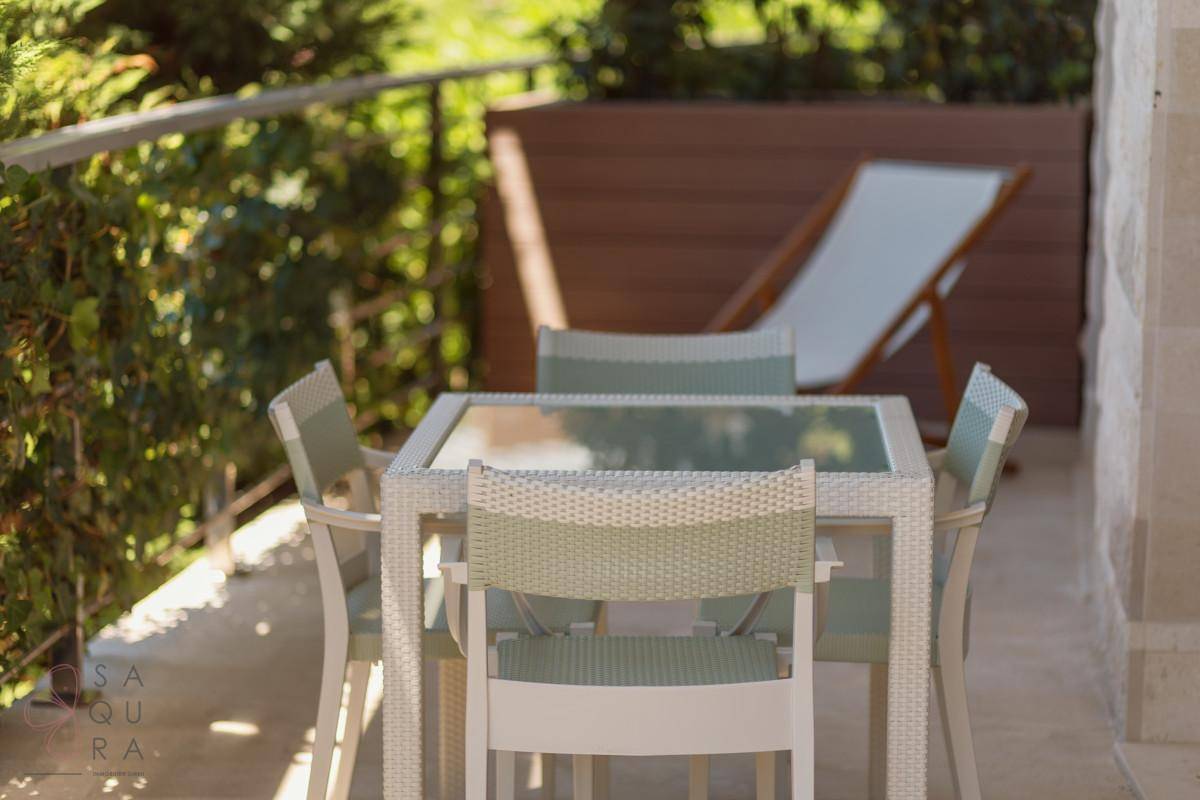 Sonniger Balkon mit Esstisch und Stühlen, umgeben von grünen Pflanzen für Mahlzeiten im Freien und Entspannung.