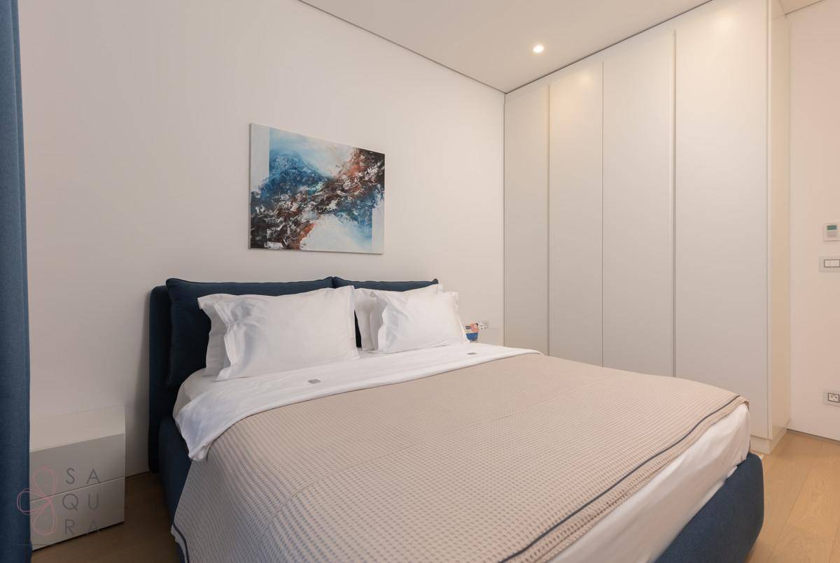 Helles Schlafzimmer mit integrierten Kleiderschränken und modernem Kunstwerk.
