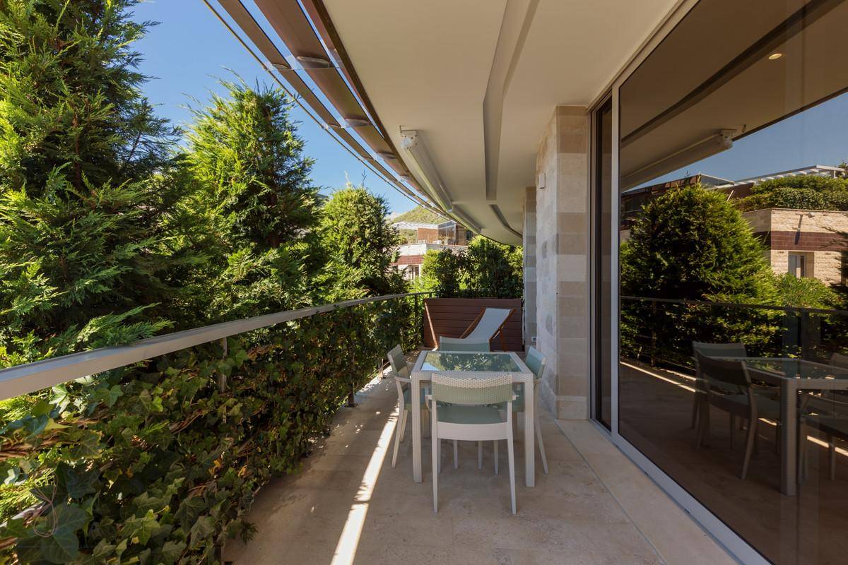 Sonniger Balkon mit Sitzgelegenheiten und üppiger Bepflanzung für Privatsphäre.