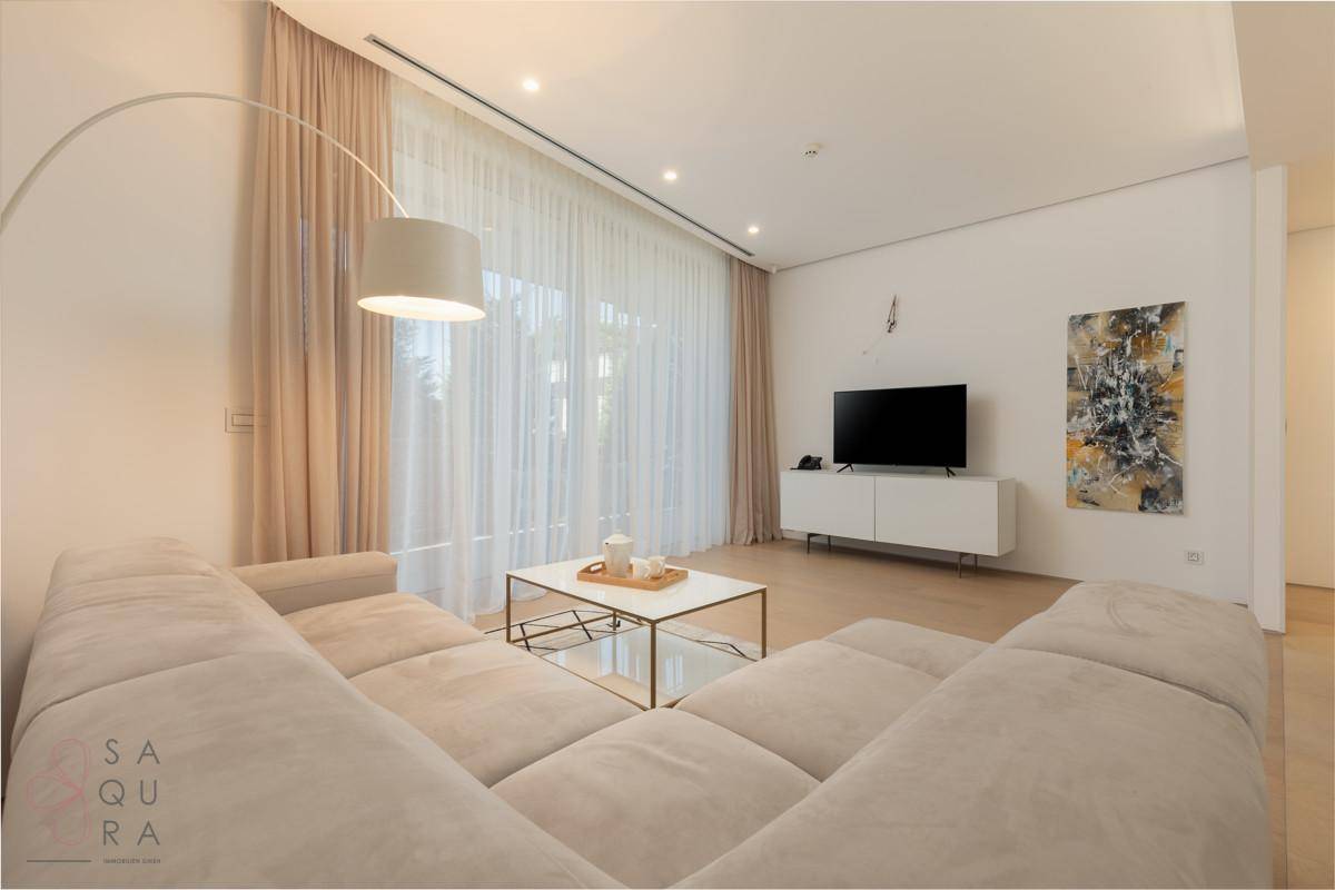 Helles Wohnzimmer mit beigem Ecksofa, modernem Couchtisch und großem Fenster.