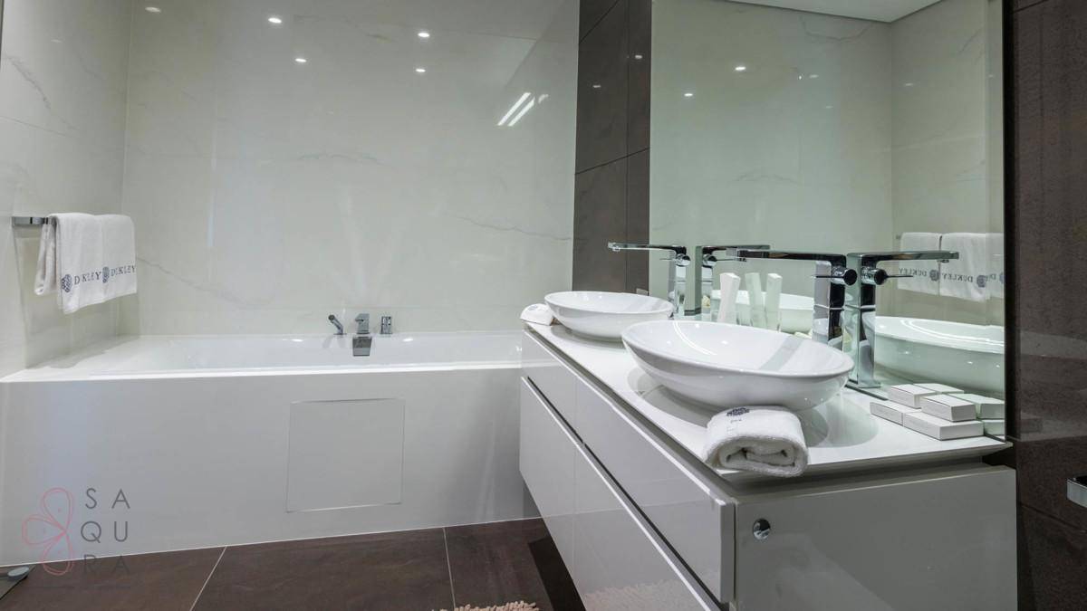 Modernes Badezimmer mit eleganter Badewanne, Doppelwaschbecken und großen Fliesen.