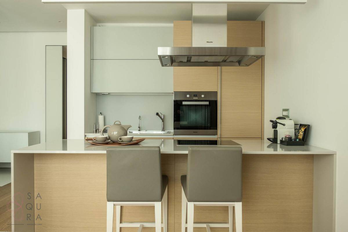 Moderne Einbauküche mit Kücheninsel, hochwertigen Geräten und stilvollen Barhockern.