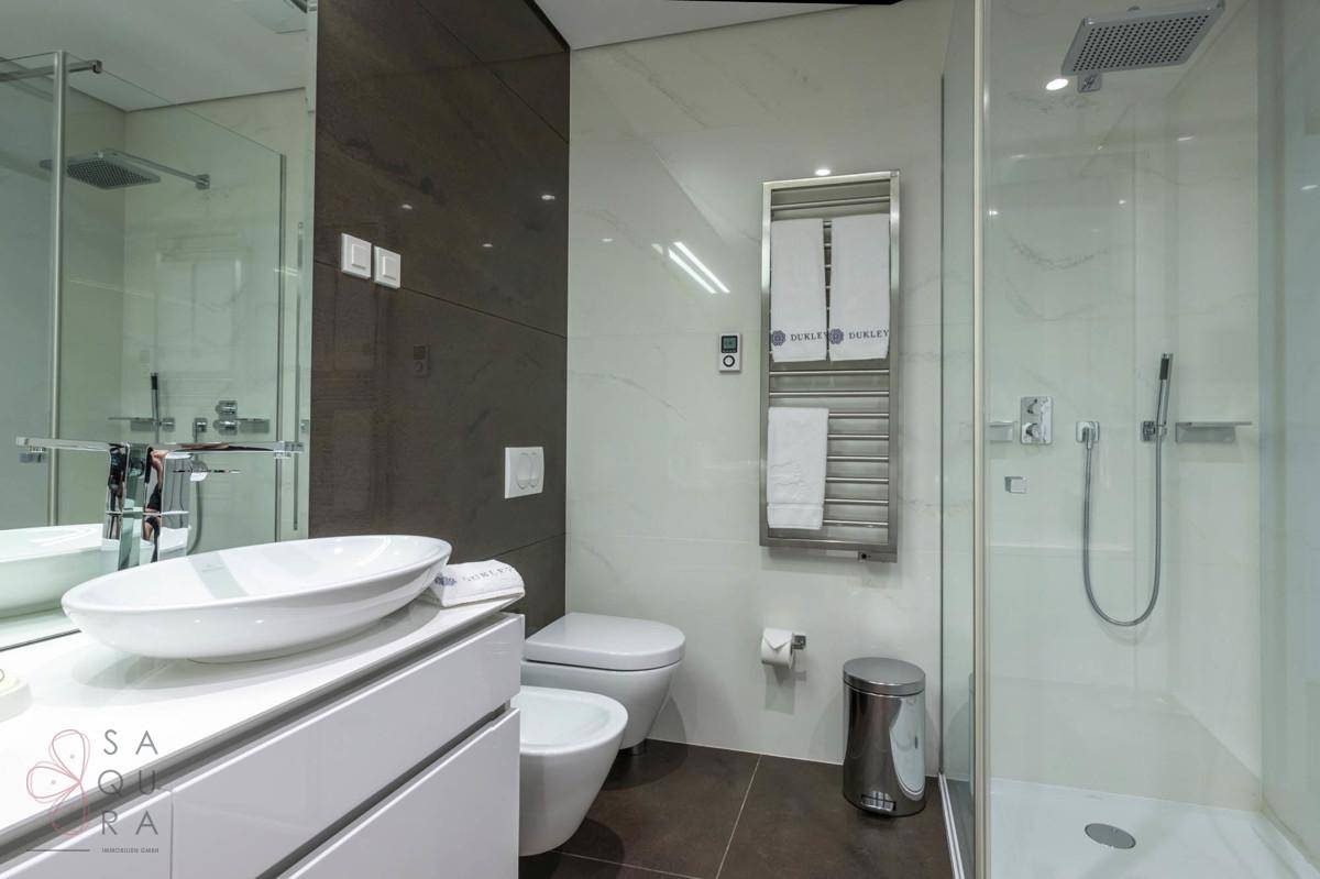 Modernes Badezimmer mit begehbarer Dusche, Toilette, Bidet und beheiztem Handtuchhalter.