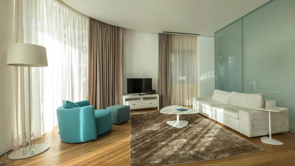 Gemütliches Wohnzimmer mit bequemen Sofas, Holzboden und großen Fenstern für viel Tageslicht.