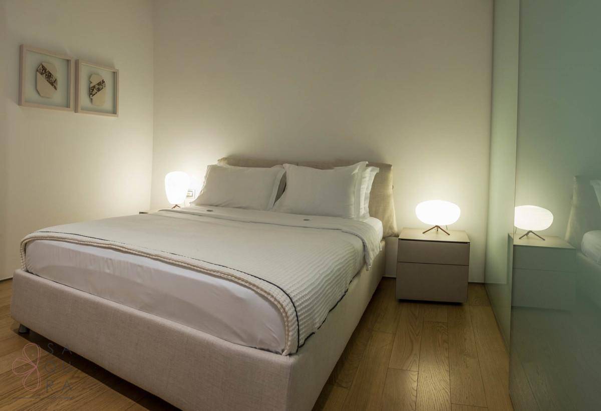 Helles Schlafzimmer mit Doppelbett, Nachttischen und elegantem Holzboden.