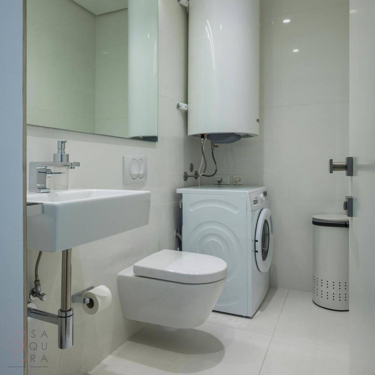 Modernes Badezimmer mit wandhängendem WC, Waschbecken und integrierter Waschmaschine.