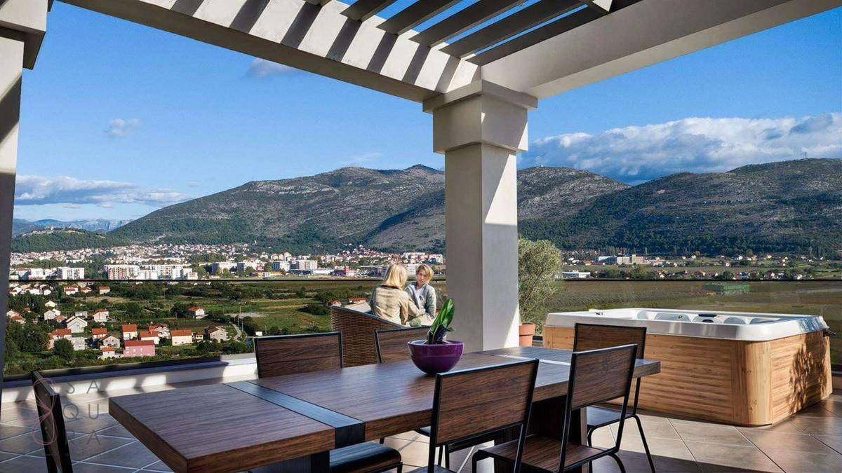 Geräumige Dachterrasse mit Whirlpool, Essbereich und Panoramablick auf Stadt und Berge.
