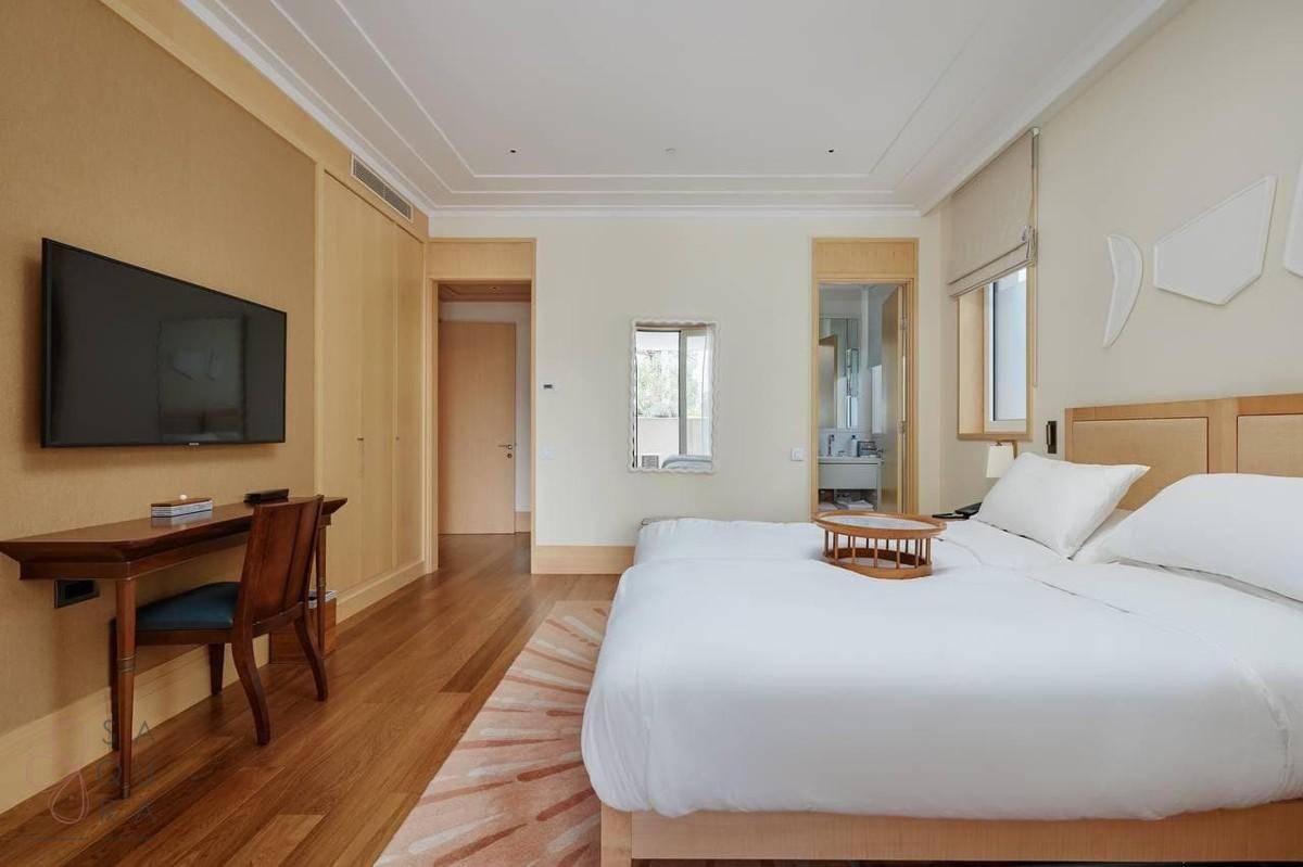 Geräumiges Schlafzimmer mit Holzboden, Schreibtisch und Blick auf das angrenzende Badezimmer.