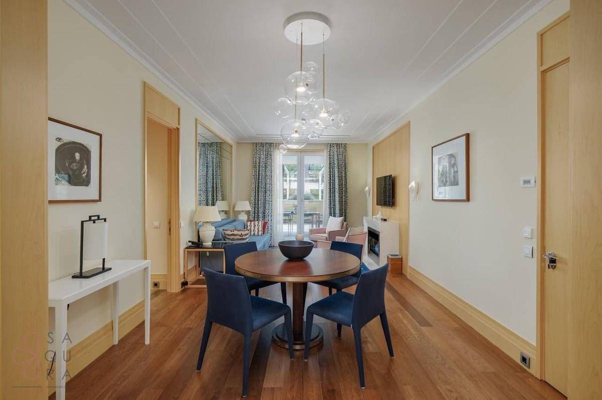 Eleganter Essbereich mit Holztisch und blauen Stühlen, offen zum Wohnzimmer und Küche.