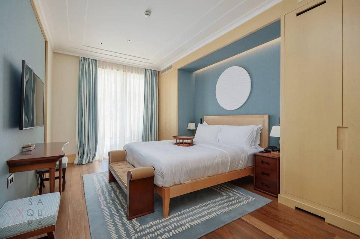 Modernes Schlafzimmer mit blauer Akzentwand, Holzboden und integrierten Kleiderschränken.