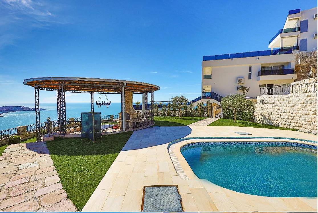 Außenbereich mit Pool, gepflasterten Wegen und einem Pavillon, der einen weiten Blick auf das Meer bietet.