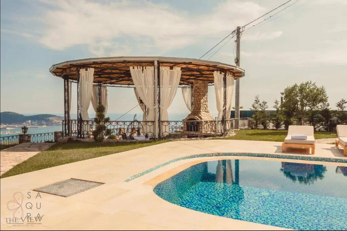 Außenbereich mit Pool und elegantem Pavillon, der einen weiten Blick auf das Meer und die Küste bietet.