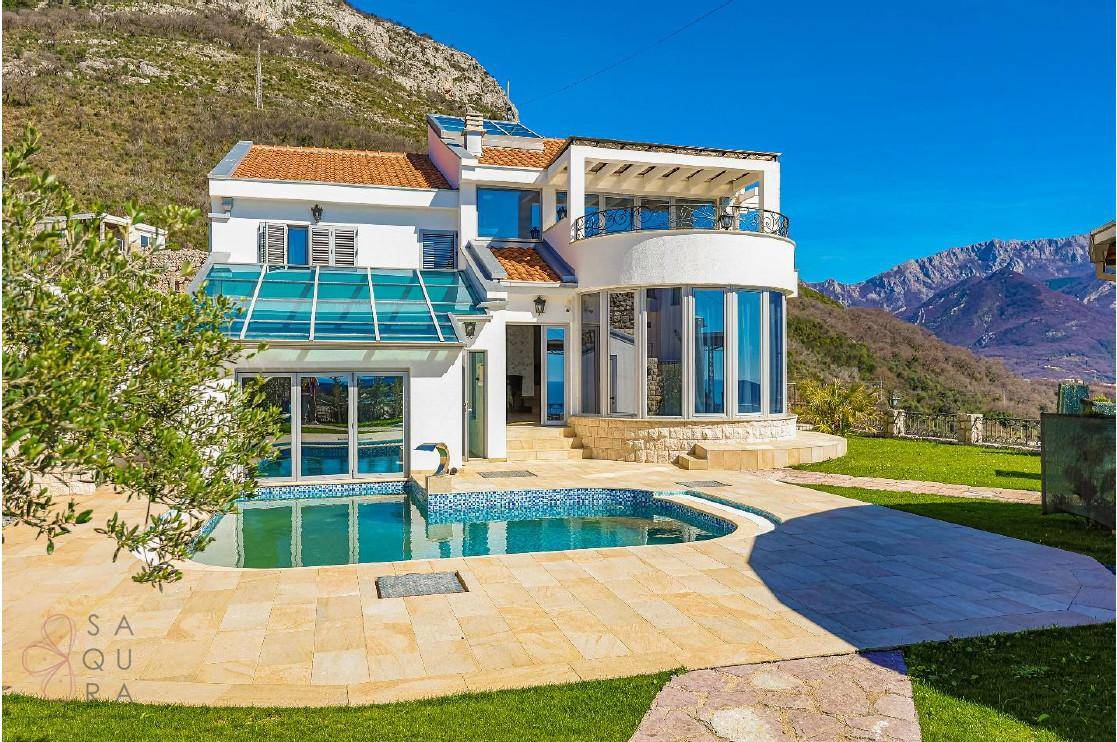 Moderne Villa mit großem Außenpool und gepflasterter Terrasse, eingebettet in eine malerische Bergkulisse.
