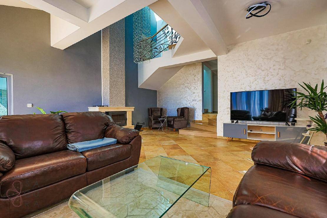 Geräumiges Wohnzimmer mit hohen Decken, Kamin und einer eleganten Treppe, die in die oberen Etagen führt.