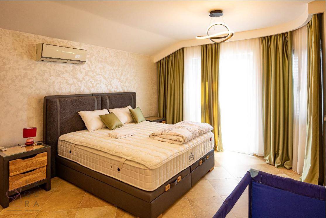 Geräumiges Schlafzimmer mit großem Bett, Klimaanlage und hellen Vorhängen, die viel Tageslicht hereinlassen.