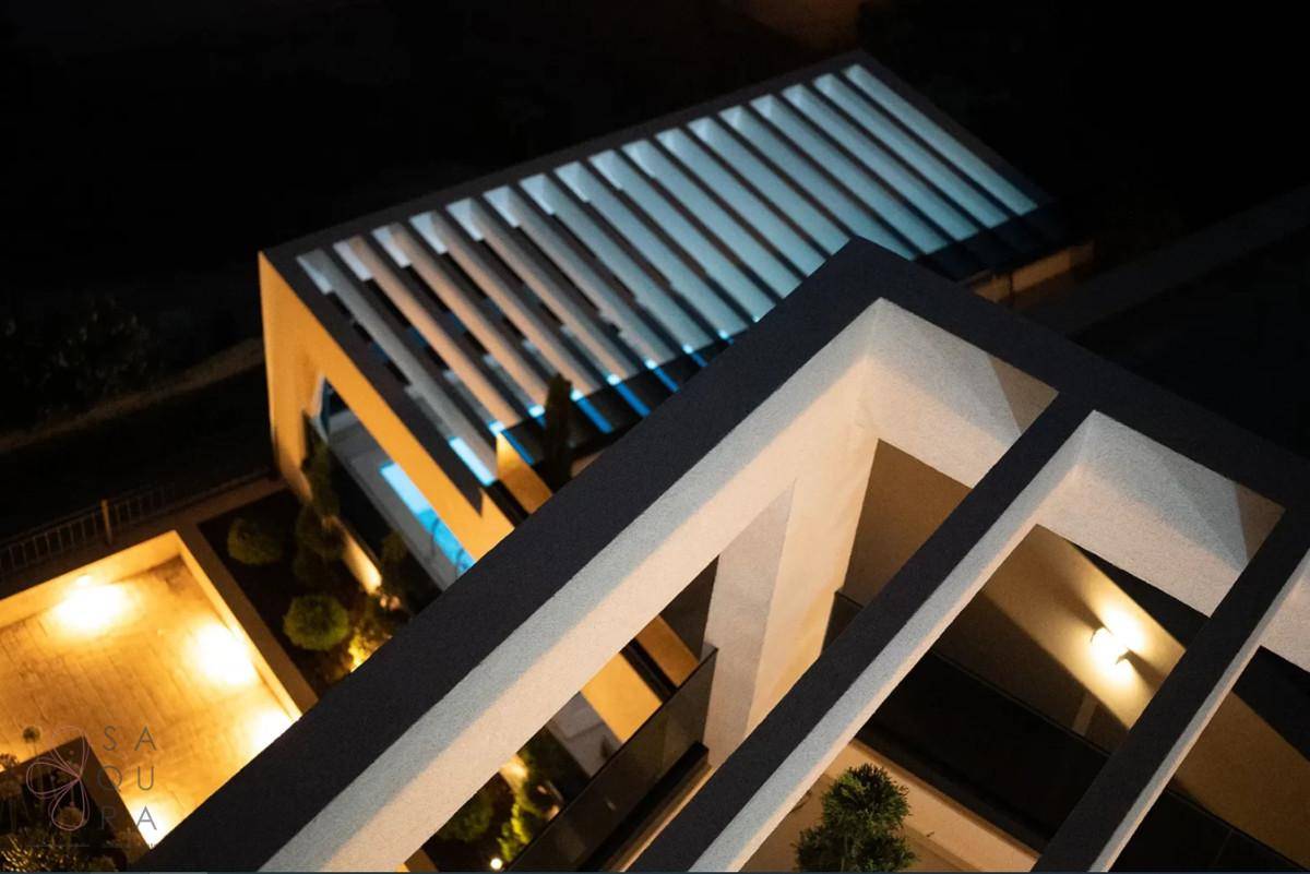 Moderne Architektur des Gebäudes bei Nacht mit beleuchteter Pergola und Poolbereich.